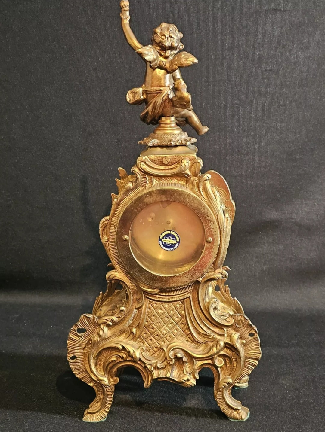 A Louis XV Style Brass Mantle Clock, Mounted with a Cherub, the Dial with Enamel